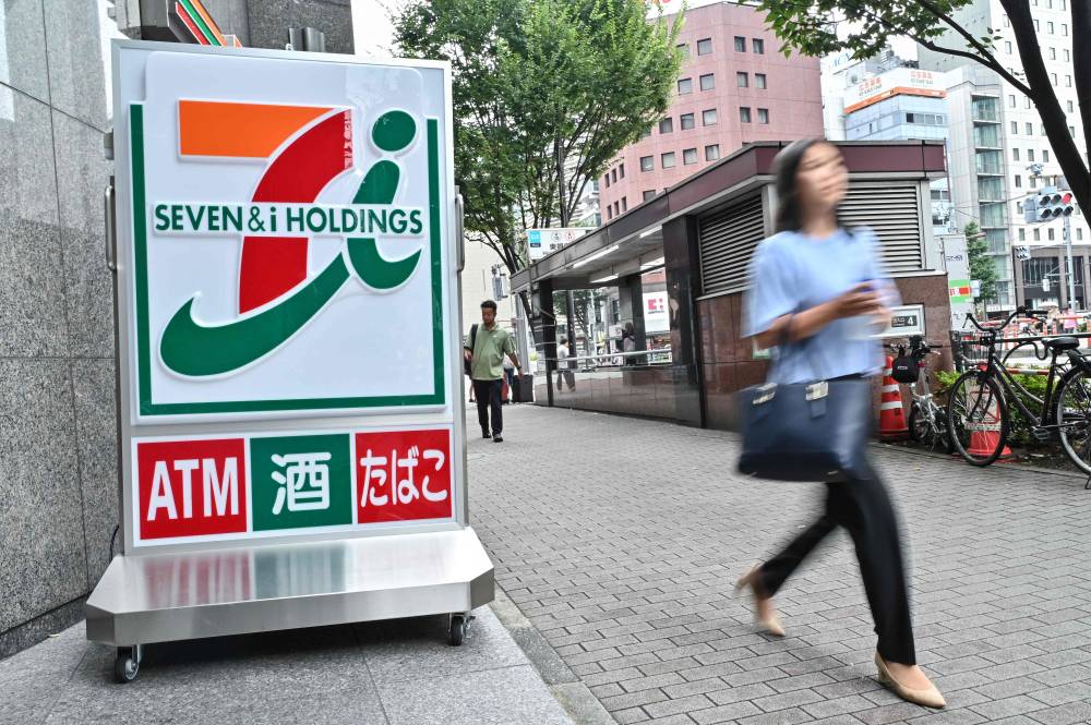 Photo for illustration purpose only. A woman walks out of a 7-Eleven convenience store along a street in central Tokyo on August 22, 2024. (Photo by Richard A. Brooks / AFP)