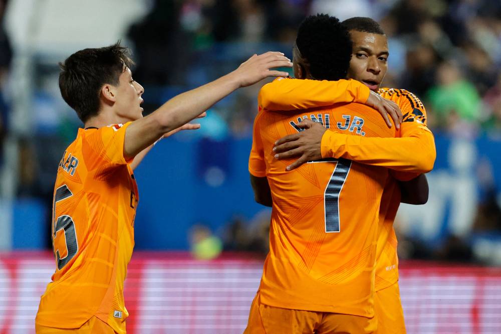 Real Madrid's French forward Kylian Mbappe (R) celebrates scoring the opening goal with Real Madrid's Brazilian forward Vinicius Junior and Real Madrid's Turkish midfielder Arda Guler (L) during the Spanish league football match between Club Deportivo Leganes SAD and Real Madrid CF at the Estadio Municipal Butarque in Leganes on November 24, 2024. (Photo by OSCAR DEL POZO/AFP)