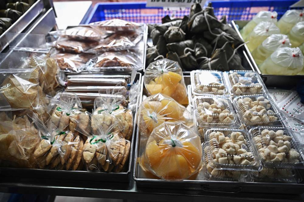 This photo taken on September 4, 2024 shows desserts packed in single-use plastic containers and bags at a traditional Thai dessert shop in Bangkok. Each year the world produces around 400 million tonnes of plastic waste, much of it discarded after just a few minutes of use. Thailand started limiting single-use plastic before the pandemic, asking major retailers to stop handing out bags for free. But the policy has largely fallen by the wayside, with little uptake among country's street food vendors. (Photo by Lillian SUWANRUMPHA/AFP)
