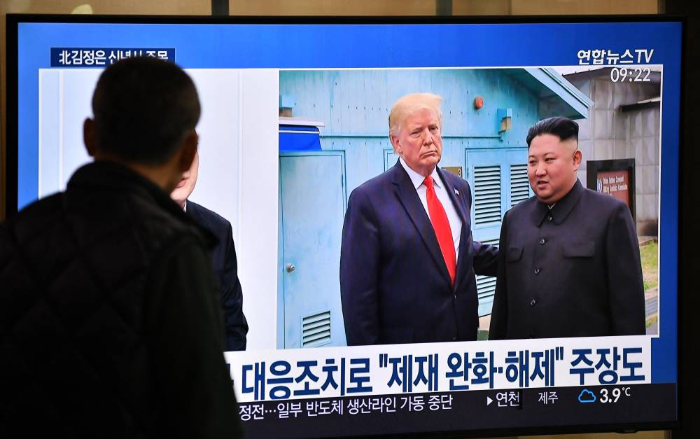 A man watches a television news programme showing file footage of a meeting between President-elect Donald Trump and North Korean leader Kim Jong Un at the truce village of Panmunjom, at a railway station in Seoul on Jan 1, 2020. - (Photo by AFP)