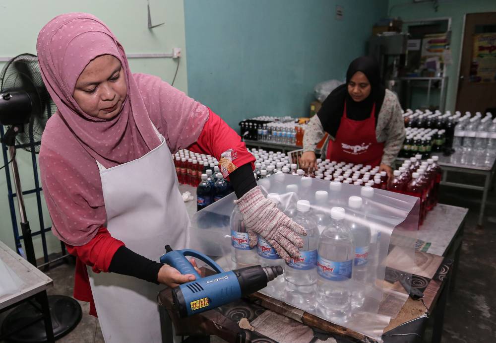 Rosniza Saaiddin carries out packaging for Zeeper carbonated drinks at her business premises in Manjung. Photo by Bernama