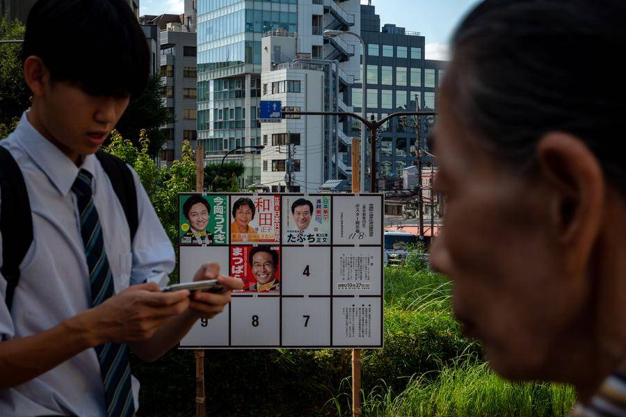 People walk past a billboard for the ongoing election campaign in Tokyo, Japan on Oct 15, 2024. - (Photo by Zhang Xiaoyu / XINHUA)