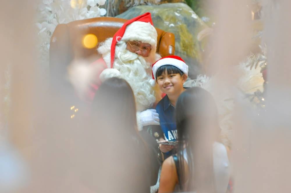Visitors take the opportunity to take pictures with Santa Claus and the stunning Christmas decorations at a shopping centre. Photo by Bernama