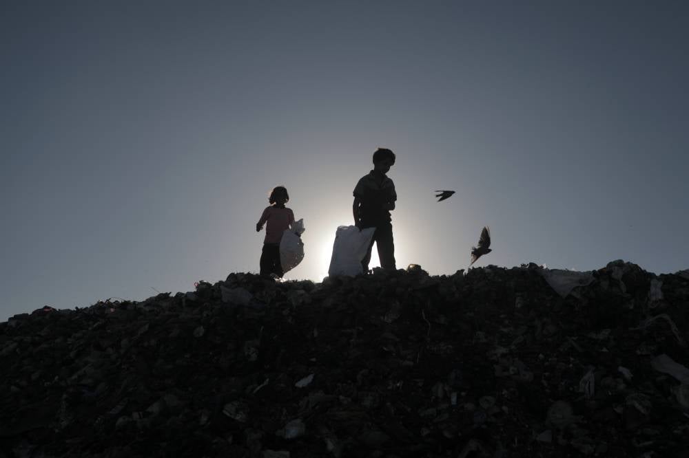 Palestinian children collect items at a garbage dump in the al-Nuseirat refugee camp in central Gaza Strip, on Dec 24, 2024. - (Photo by Rizek Abdeljawad / Xinhua)