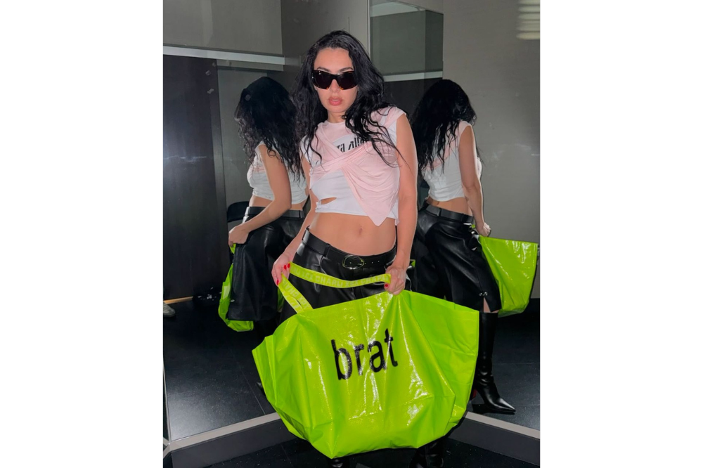 Charli XCX with one of her brat merchandise while resembling brat fashion that was popular in the early 2000s.
