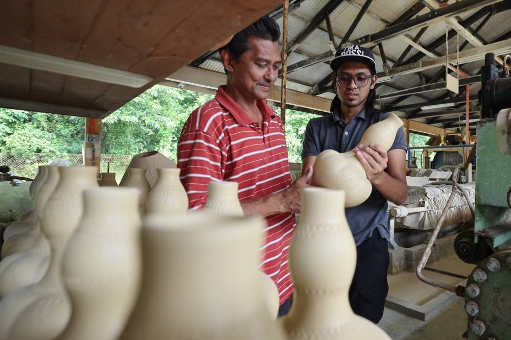 Muhammad Luqman NulHakim (right) with his father Mohd Sa'ya Mat Jahari looking at the clay-based products at the Perak Malaysian Handicraft Development Corporation. - Photo by Bernama