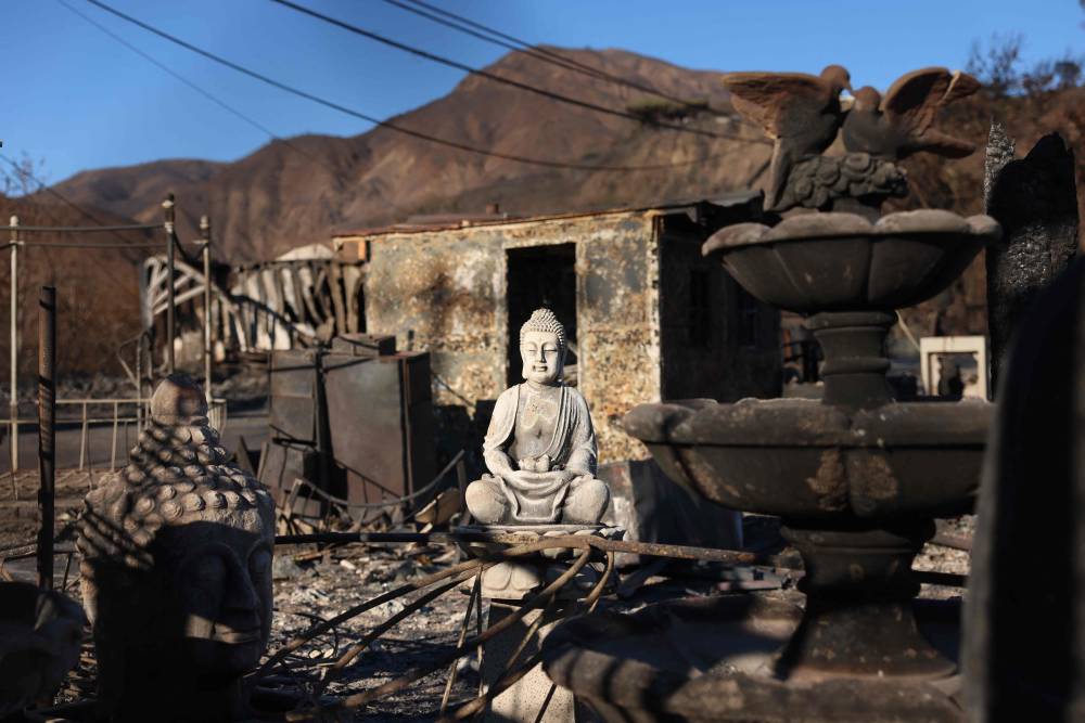 A Buddha statue sits in a burned lot as the Palisades Fire continues to grow in Los Angeles, California, on January 12, 2025. (Photo by David Swanson / AFP)