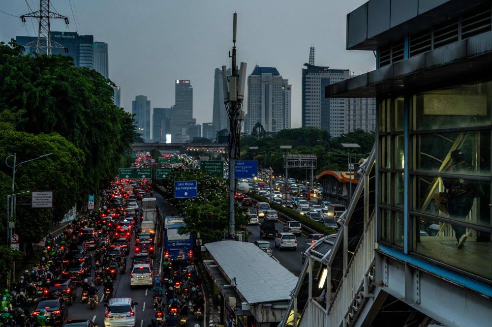 This picture taken on November 13, 2024 shows commuters driving on a roads heading out of Jakarta during the evening rush hour. Scrolling on social media, Indonesian moviegoer Jessica Sihotang stumbled across a film depicting a fellow woman in her 30s struggling to make the dream of buying a Jakarta home a reality. (Photo by BAY ISMOYO/AFP)