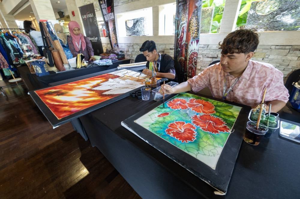 Muhammad Hakim Iskandar Jasni (right) developed a stronger interest in the field after receiving encouragement from his parents, who also run the business at the Langkawi Craft Complex. Photo by Bernama