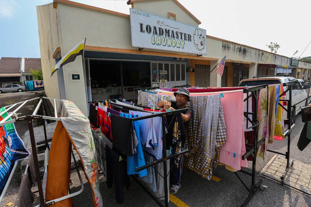 Mohd Rizal Mohd Rajab drying laundry at his shop, Loadmaster Laundry, recently. Photo by Bernama