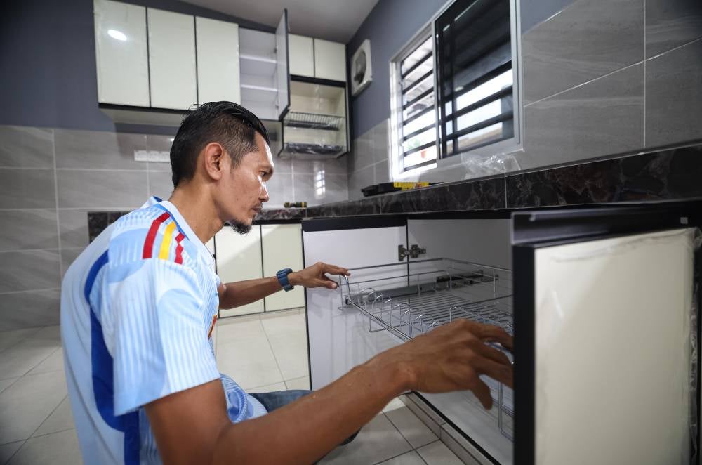 Hasrul Affendi Norizan, 44, installing kitchen cabinets atTaman Klebang Putra recently. Photo by Bernama