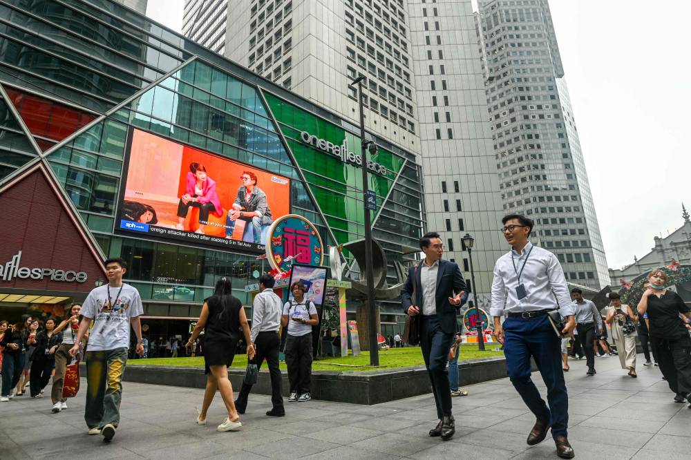 People walk on the street during lunch break at Raffles Place in Singapore on January 22, 2025. (Photo by Roslan RAHMAN / AFP)