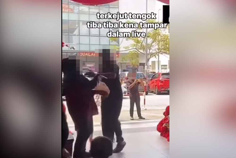 A screenshot from a viral video showing a man slapping his wife at a shopping centre.
