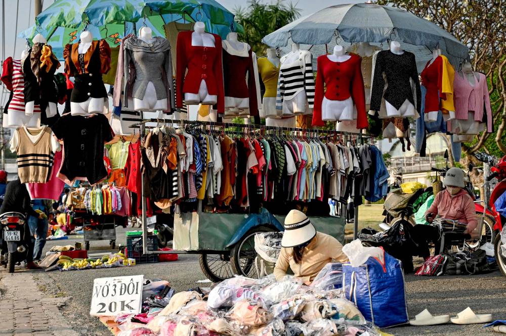 This photo taken on December 23, 2024 shows vendors waiting for customers at a street market outside the Pouyuen Vietnam factory, owned by Taiwanese shoemaker Pou Chen, in Ho Chi Minh City. (Photo by Nhac NGUYEN/AFP)