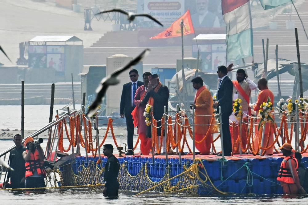 India's Prime Minister Narendra Modi (centre) arrives to take a holy dip in the sacred waters of Sangam, the confluence of Ganges, Yamuna and mythical Saraswati rivers during Maha Kumbh Mela festival, in Prayagraj. Photo by Idrees Mohammed/AFP