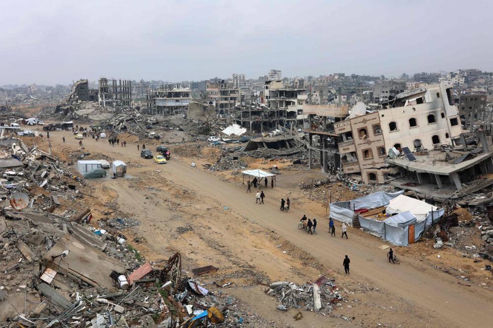 People walk amid collapsed buildings along Saftawi street in Jabalia in the northern Gaza Strip on Feb 5, 2025. (Photo by Omar AL-QATTAA / AFP)