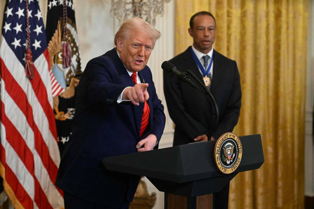 US President Donald Trump speaks next to golfing legend Tiger Woods during a reception for Black History Month in the East Room of the White House on February 20, 2025 in Washington, DC. (Photo by Jim WATSON / AFP)