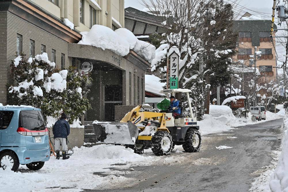 This photo taken on January 31, 2025 shows a man using heavy machinery to clear snow from a street in the ski resort town of Hakuba, Nagano prefecture. (Photo by Richard A. Brooks/AFP)
