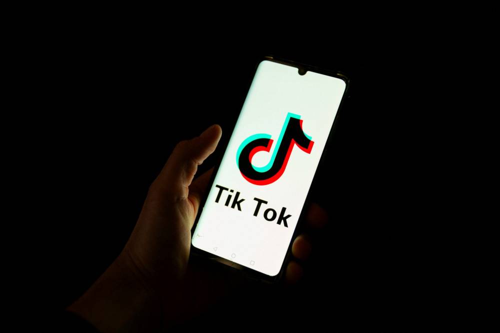 This photograph taken on April 19, 2024 shows a man holding a smartphone displaying the logo of Chinese social media platform Tiktok in an office in Paris. - (Photo by Antonin Utz / AFP)
