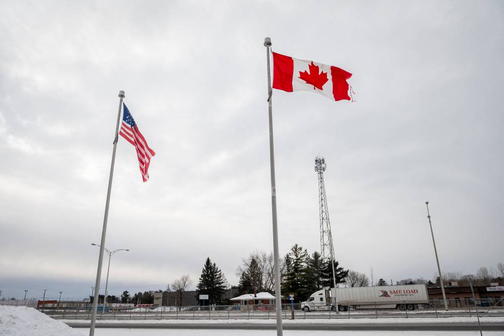 The Canadian and US flags fly near the Canada-US border in Blackpool, Quebec, Canada, on February 2, 2025. (Photo by ANDREJ IVANOV / AFP)