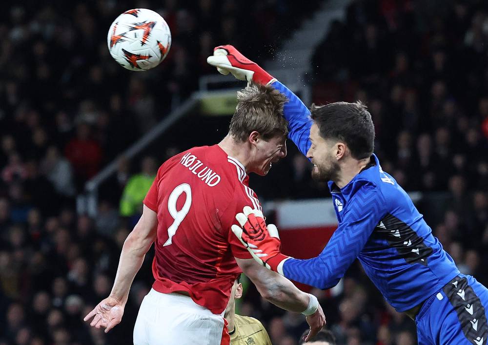 Manchester United's Danish striker #09 Rasmus Hojlund clashes with Real Sociedad's Spanish goalkeeper #01 Alex Remiro as he clears the ball during the UEFA Europa League Last 16 Second Leg football match between Manchester United and Real Sociedad at Old Trafford stadium in Manchester, north west England, on March 13, 2025. (Photo by Darren Staples / AFP)
