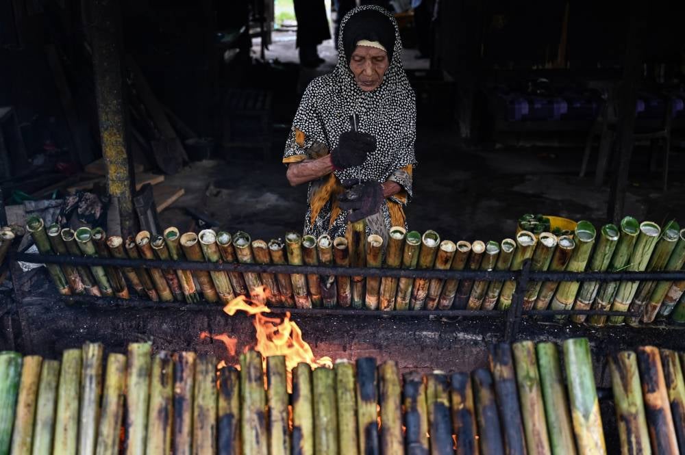 Trader Atikah Salleh, 78, prepares lemang to sell to the public during a tour in Kijal here. Photo by Bernama
