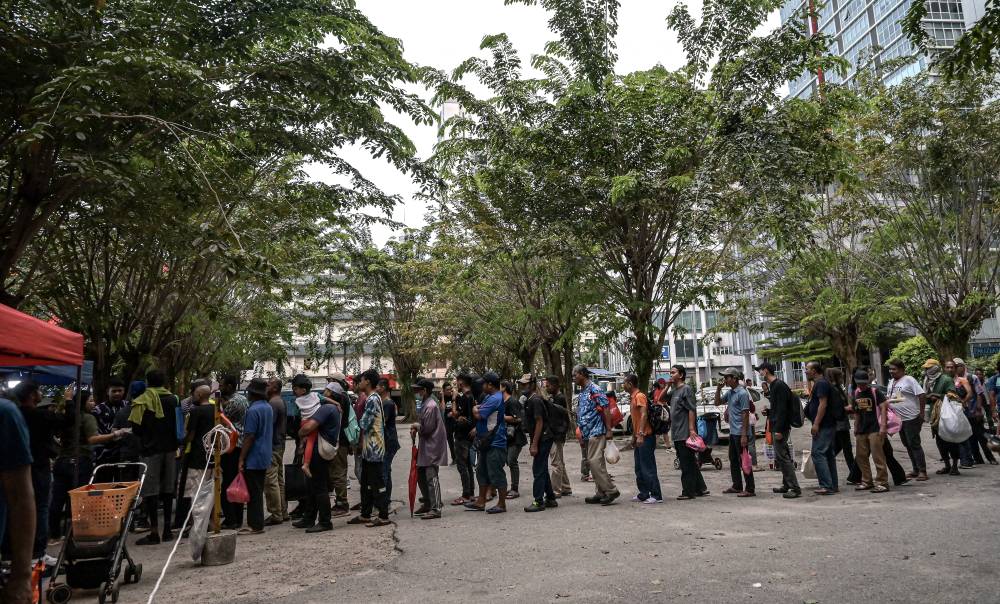 The asnaf community collected food supplies distributed by non-governmental organisations (NGOs) as their iftar meal at Lorong Haji Taib, Chow Kit, recently. Photo by Bernama