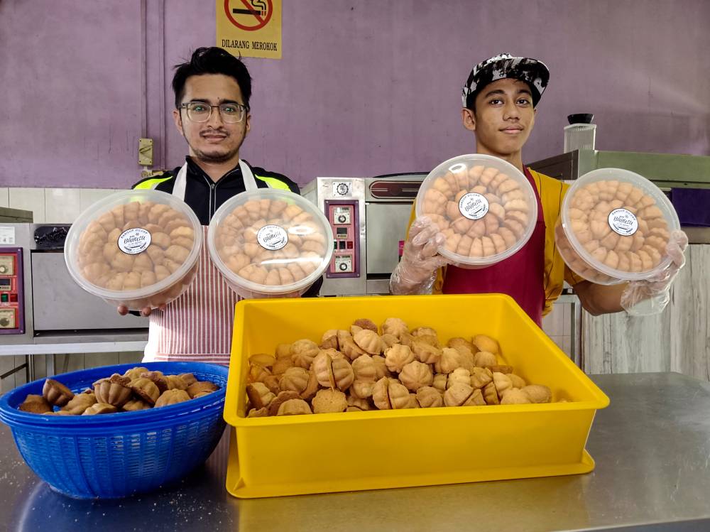 Muhammad Najmi Amzairy (right) and Arif Fathilah Othman showing the bahulu they made at their workshop in Melaka Pindah. Photo by Bernama