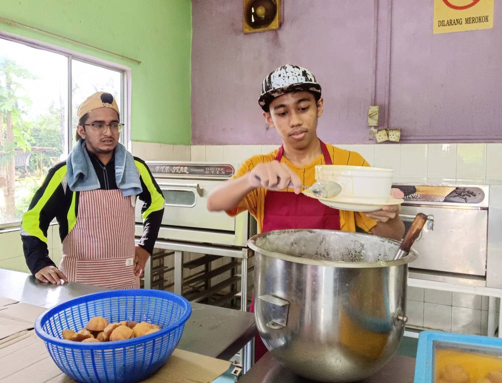 Muhammad Najmi Amzairy (right) and Arif Fathilah Othman making the bahulu at their workshop in Melaka Pindah. Photo by Bernama