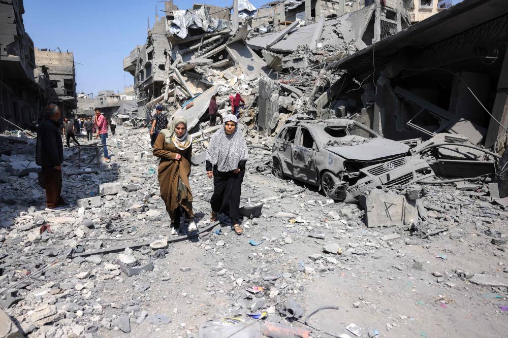 People walk amid the rubble of a building destroyed in an overnight Israeli strike in Jabalia, in the northern Gaza Strip on March 18. - (Photo by AFP) 
