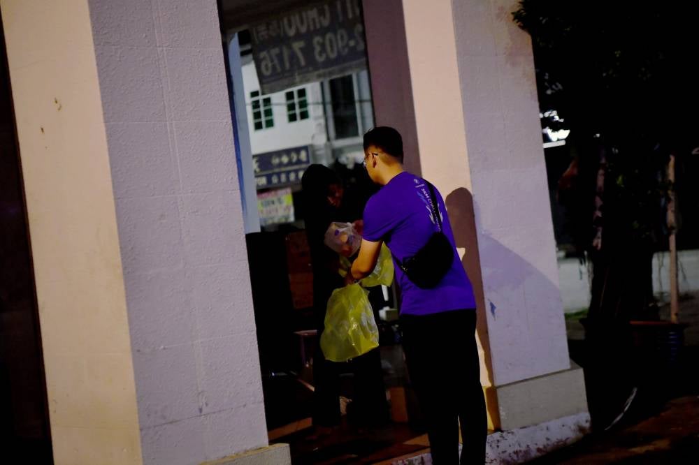 Sahur With Homeless Project volunteer distributes food to the needy. Photo by Bernama