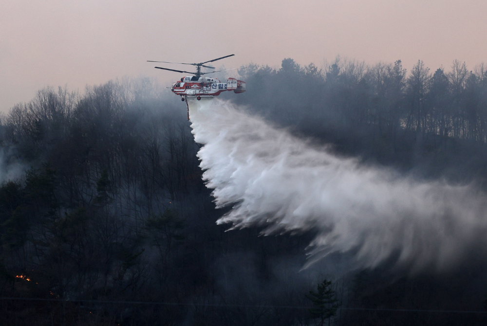 A helicopter performs a water drop on a wildfire in North Gyeongsang province, South Korea, March 22, 2025. (NEWSIS via Xinhua)