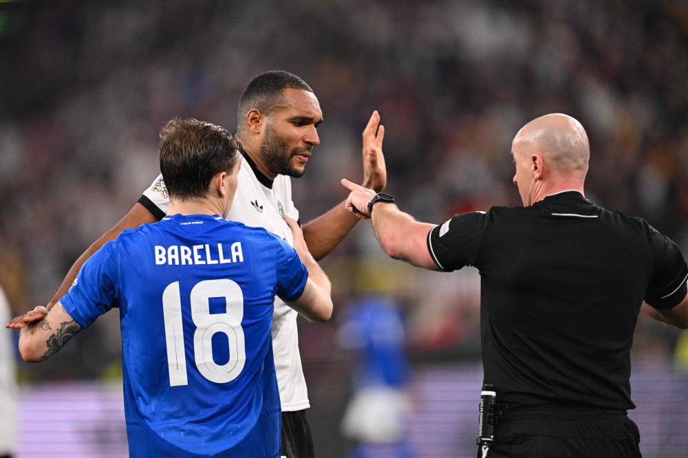 Polish referee Szymon Marciniak points to Germany's defender #04 Jonathan Tah next to Italy's midfielder #18 Nicolo Barella during the UEFA Nations League quarter-final second leg football match Germany v Italy in Dortmund, western Germany on March 23, 2025. (Photo by Kirill KUDRYAVTSEV / AFP)