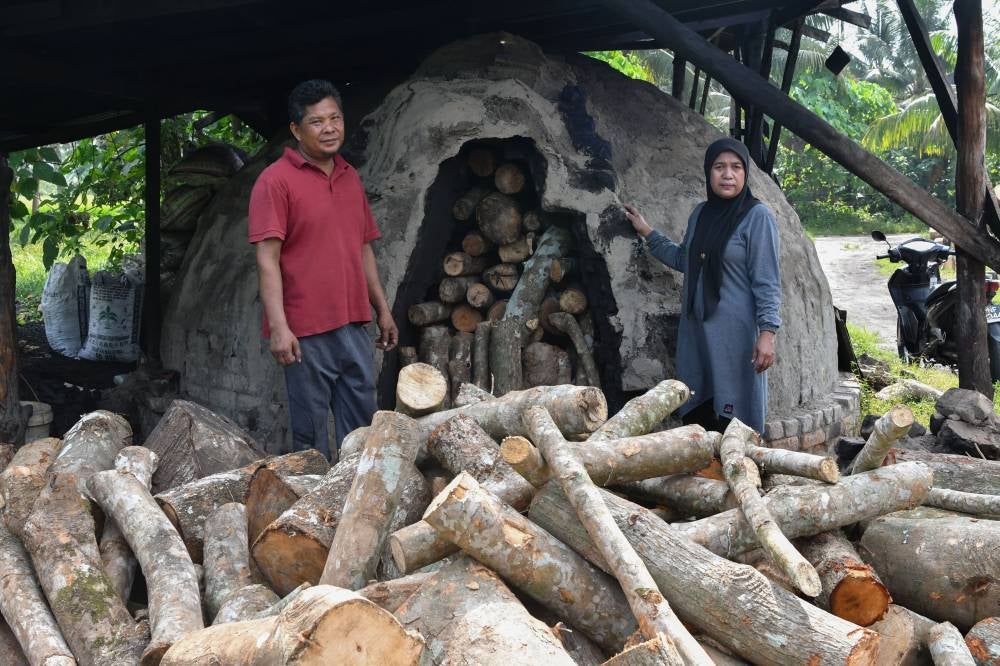 Charcoal entrepreneur Nazri Mohd Sohor (left) and his wife Pazuriatiayu Paudin. Photo by Bernama