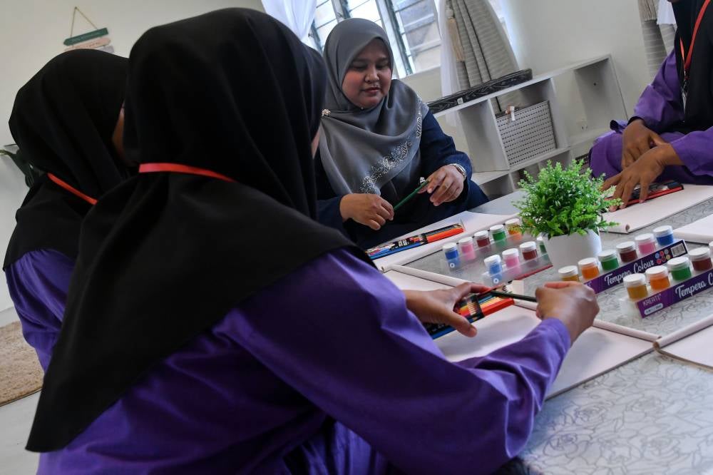 Former Puspen Bachok client who is also a Peer Mentor Nik Affezah Nik Ab Ghani, 45, (centre) conducting activities with Puspen clients. Photo by Bernama