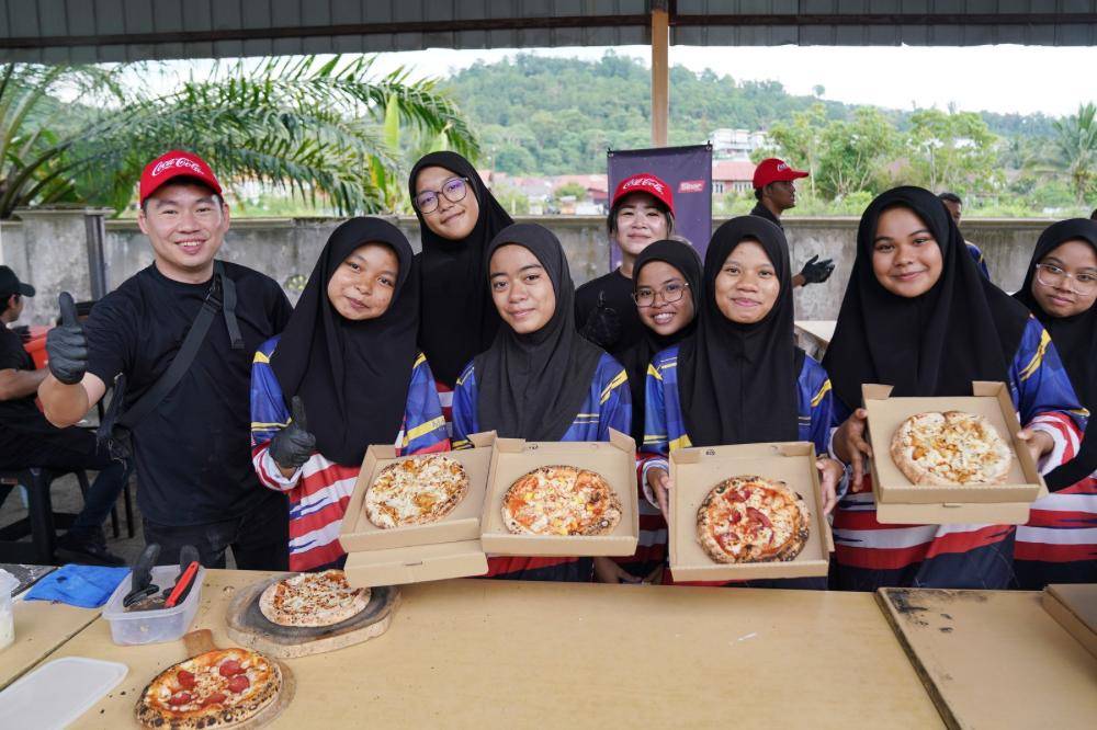 Students proudly display their freshly baked pizzas.