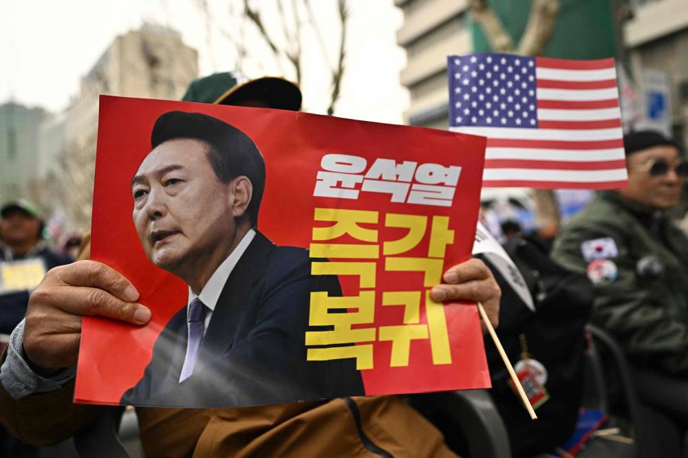 Supporters of impeached South Korean President Yoon Suk Yeol hold placards during a rally on a street in Seoul on April 2, 2025. - (Photo by PEDRO PARDO / AFP)