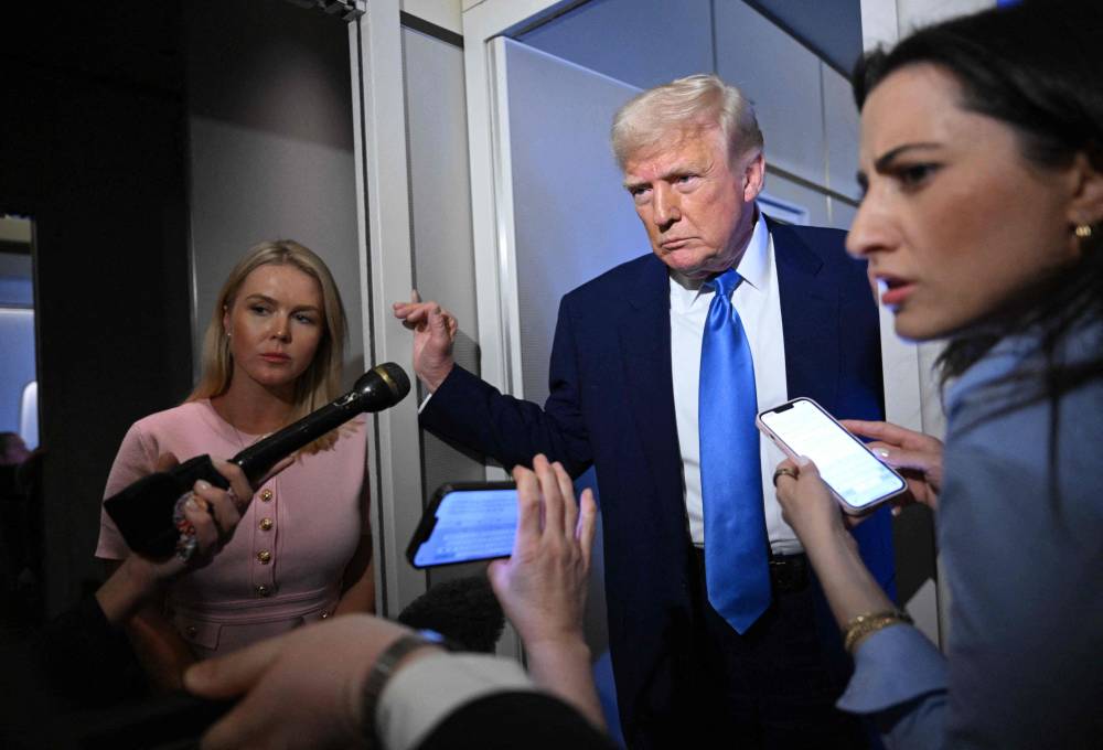 White House Press Secretary Karoline Leavitt listens (left) as US President Donald Trump speaks to reporters while in flight on Air Force One, en route to Joint Base Andrews. Photo by Mandel Ngan/AFP