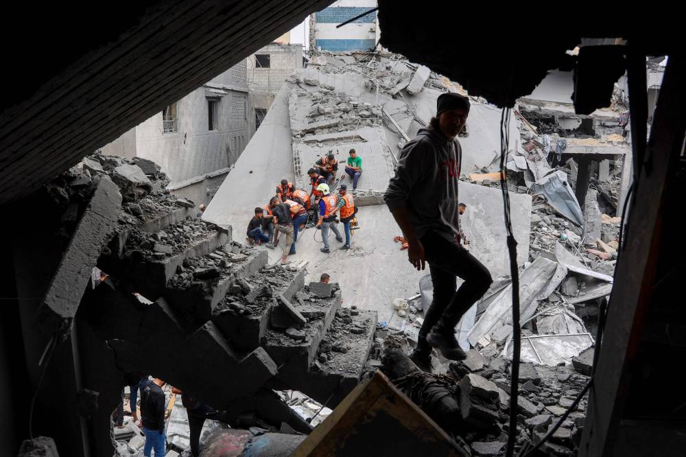 A man walks amids the rubble of a building as Palestinian rescuers work at the site of an Israeli strike on a residential area in Gaza City's Shujaiyya neighbourhood, on April 9, 2025. - (Photo by OMAR AL-QATTAA / AFP)