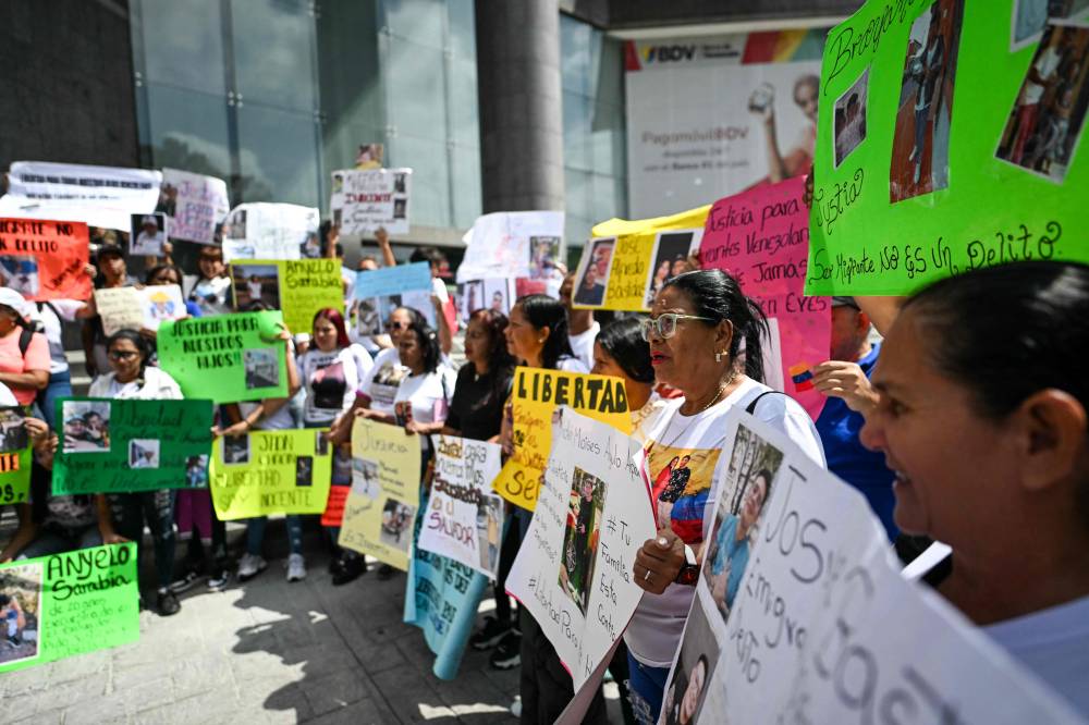 Relatives of Venezuelan migrants deported from the US to a maximum security prison in El Salvador hold signs during a demostration in front of the United Nations building in Caracas on April 9, 2025. - (Photo by JUAN BARRETO / AFP)