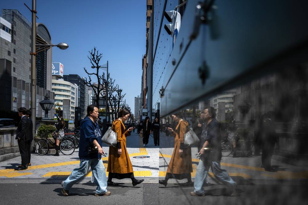 Pedestrians walk along a street in Osaka on April 14, 2025. (Photo by Philip FONG / AFP)
