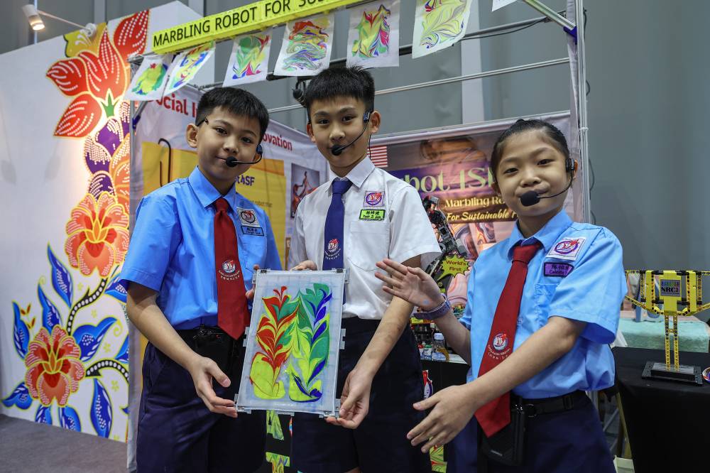 Sekolah Jenis Kebangsaan (C) Jalan Davidson pupils (from left) Yevgen Ngui, 11, Yeoh Zi Jian, 12, and Celeste Tan, 10, proudly showing their own art work using their Marbling Robot For Sustainable Future (MarBot4SF) creation at the Malaysia Open House Exhibition Asean 2025 held in conjunction with the 12th Asean Finance Ministers and Central Bank Governors Meeting (AFMGM) 2025 at the Kuala Lumpur Convention Centre recently. Photo by Bernama