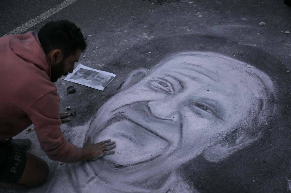 Argentine artist Javier Sativa draws the face of the late Pope Francis on a street in front of the entrance of the Buenos Aires Cathedral on April 21, 2025. (Photo by JUAN MABROMATA / AFP)