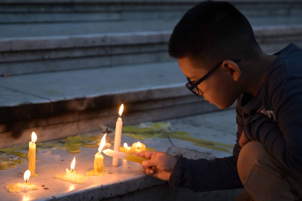 A young man lights a candle at an altar in front of the entrance of the Buenos Aires Cathedral on April 21, 2025. (Photo by JUAN MABROMATA / AFP)