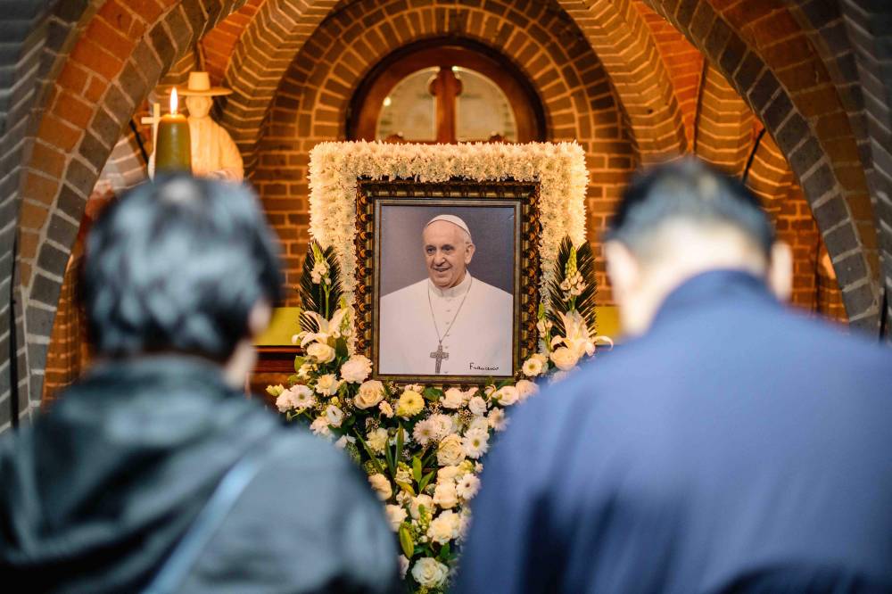 People pay their respects in front of a portrait of Pope Francis displayed inside Myeongdong Cathedral in Seoul. Photo by Anthony Wallace/AFP