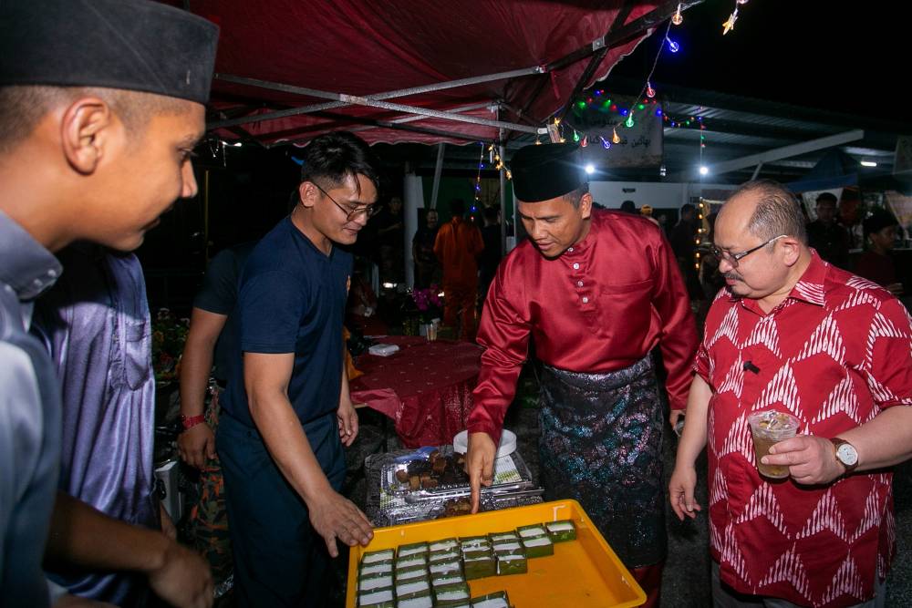 JBPM director-general Datuk Nor Hisham Mohammad (three, left) with senior political secretary to the Prime Minister Datuk Seri Shamsul Iskandar Mohd Akin visit food stalls during the Hari Raya celebration at the JBPM Headquarters, Persiaran Meru Utama, yesterday. - Photo by Bernama
