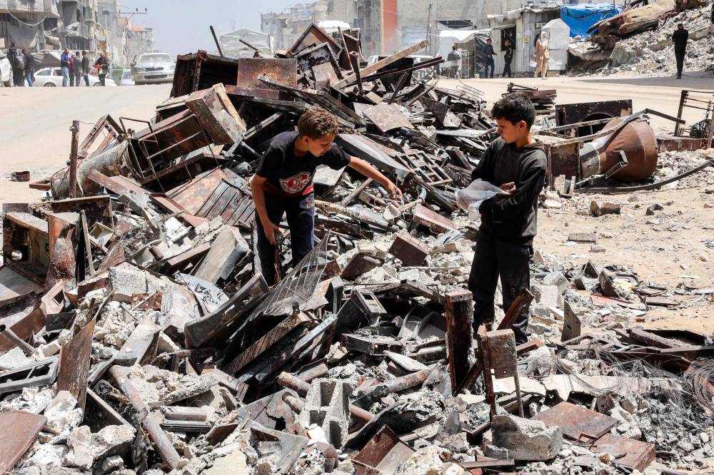 A boy searches a mound of scrap along the side of a road in Gaza City on April 21, 2025. - (Photo by OMAR AL-QATTAA / AFP)