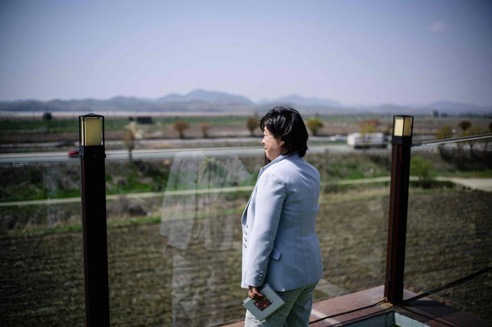 In this photo taken on April 24, 2025, Daonsoop cafe founder Lee Oh-sook looks towards the mountains of North Korea from her establishment, built less than two kilometres from the North Korean border in Paju, north of Seoul. Daonsoop cafe is so close to the North Korean border that to obtain the building permit, its owners had to construct the property with a bunker and fortified positions for tanks. (Photo by ANTHONY WALLACE/AFP)