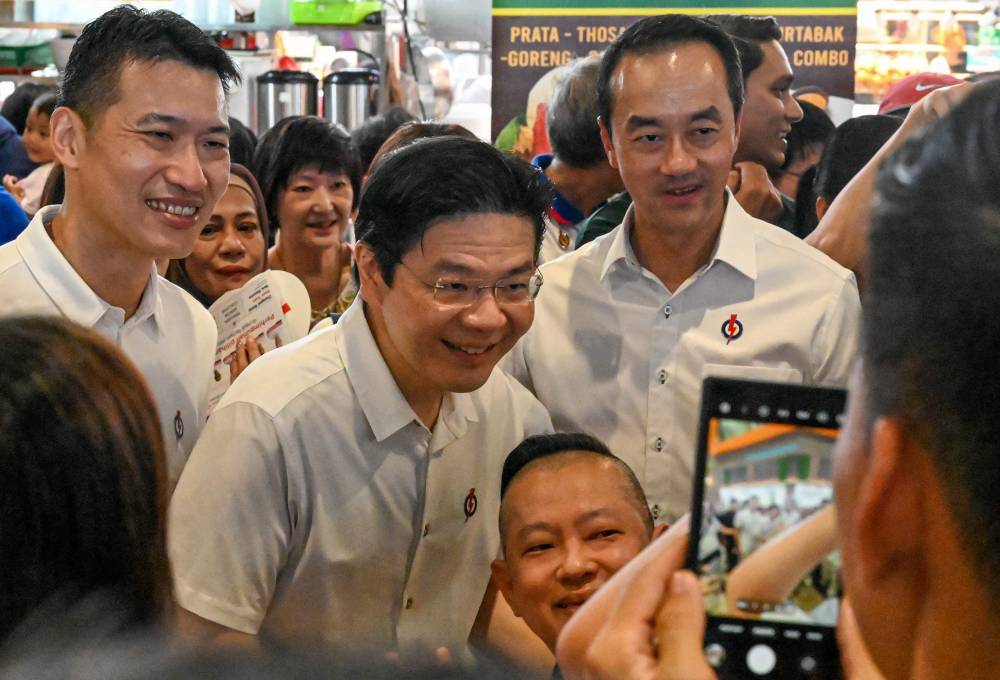 Singapore's Prime Minister and secretary-general of the ruling People's Action Party (PAP) Lawrence Wong (C) poses with residents of Tampines estate during a campaign event on April 30, 2025 in Singapore, ahead of the upcoming election. (Photo by Roslan RAHMAN / AFP)