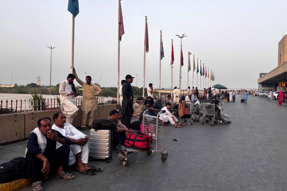 Passengers wait outside at Jinnah International airport after all domestic and international flights were cancelled in Karachi on May 7, 2025. (Photo by Asif HASSAN / AFP)